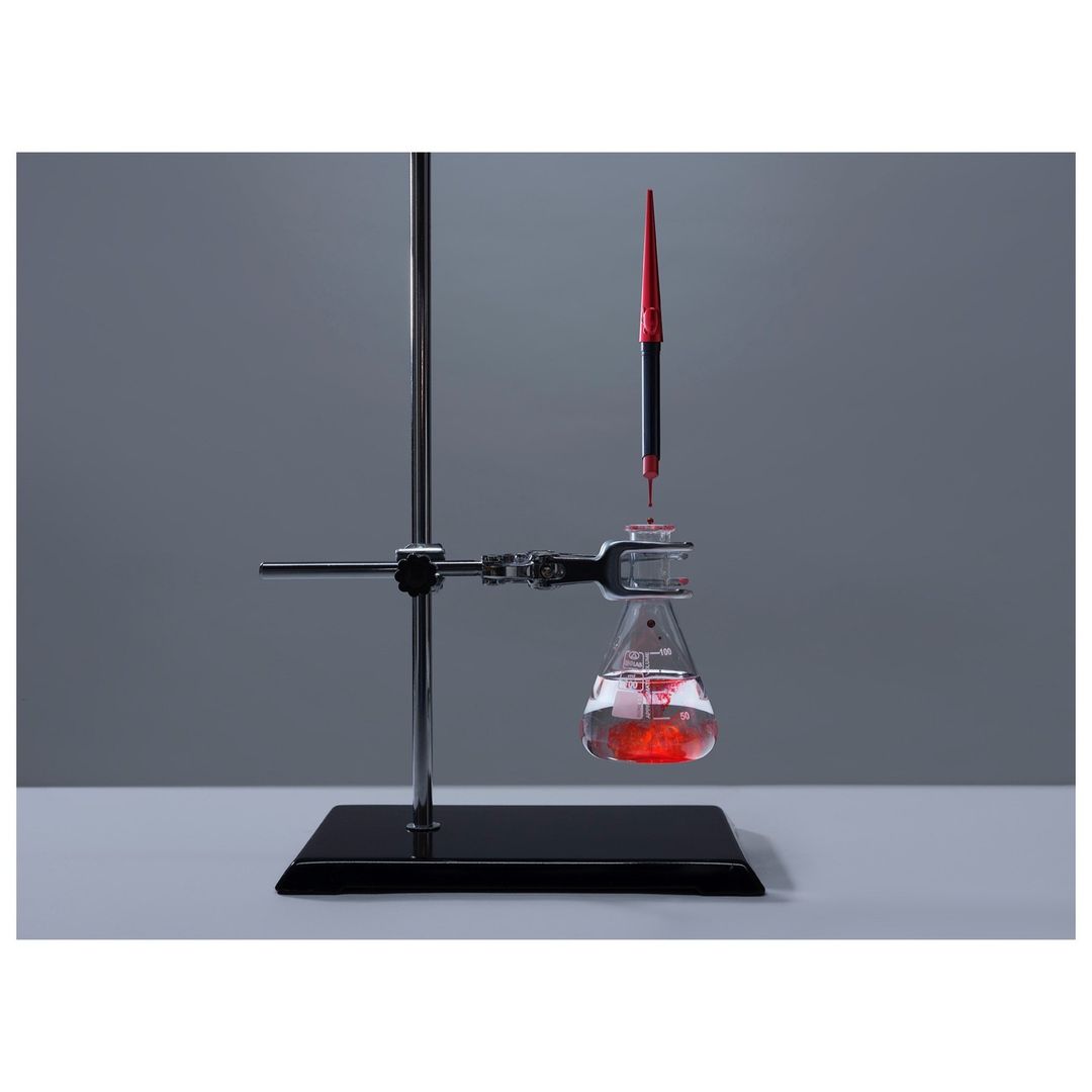 Close-up of a laboratory setup with a flask containing a red liquid being filled by a pipette, showcasing chemistry or science concept.