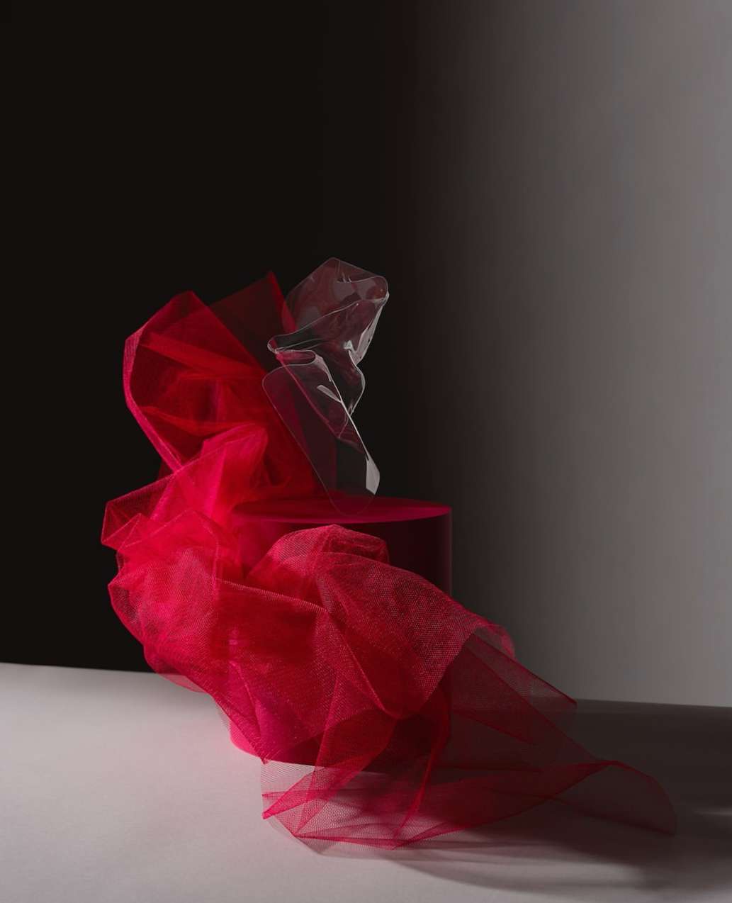 Dramatic studio shot: vibrant pink fabric cascades from a platform, illuminated against a contrasting dark backdrop. Abstract and visually striking.