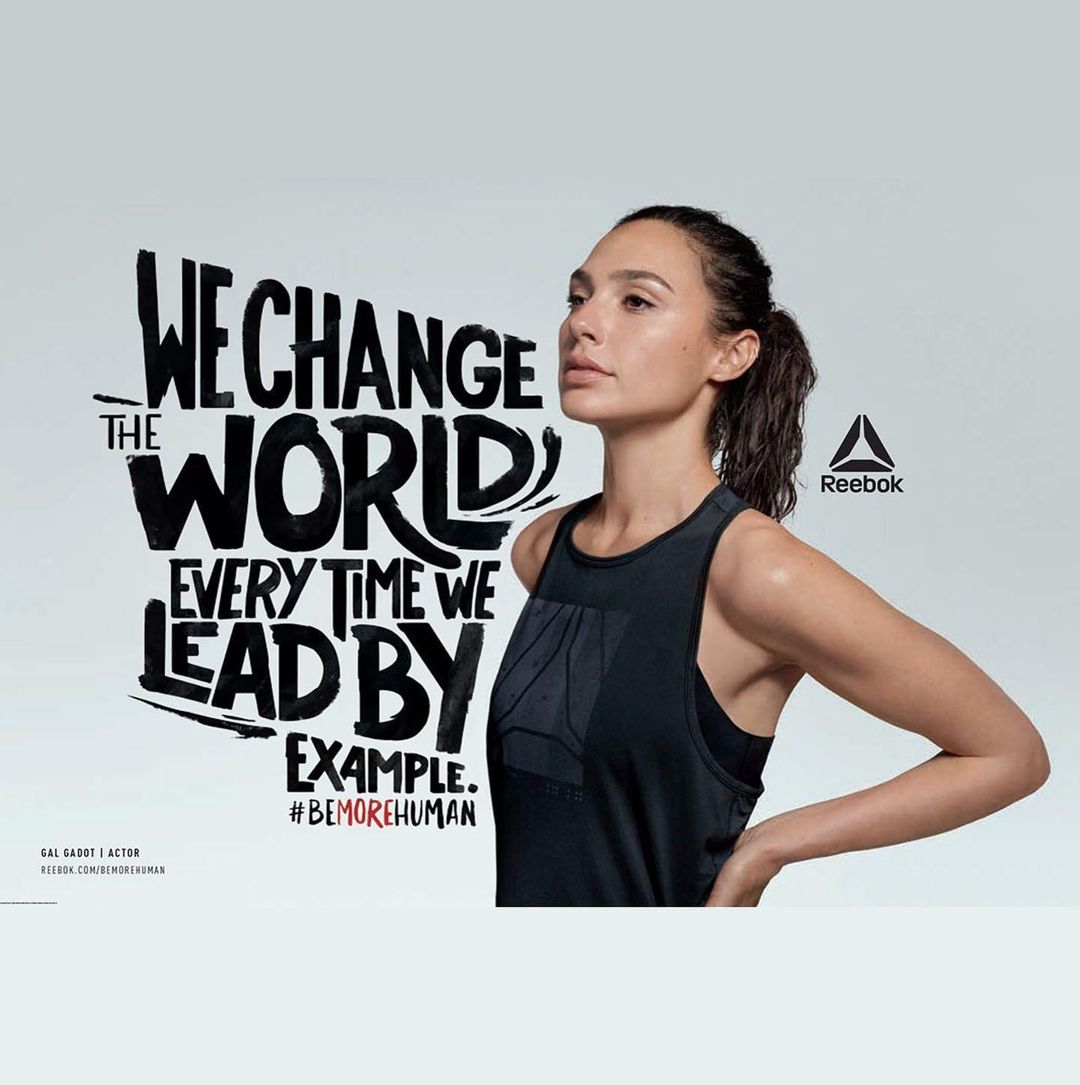 Gal Gadot in athletic wear poses next to Reebok logo and inspiring text about leading by example on a white background.
