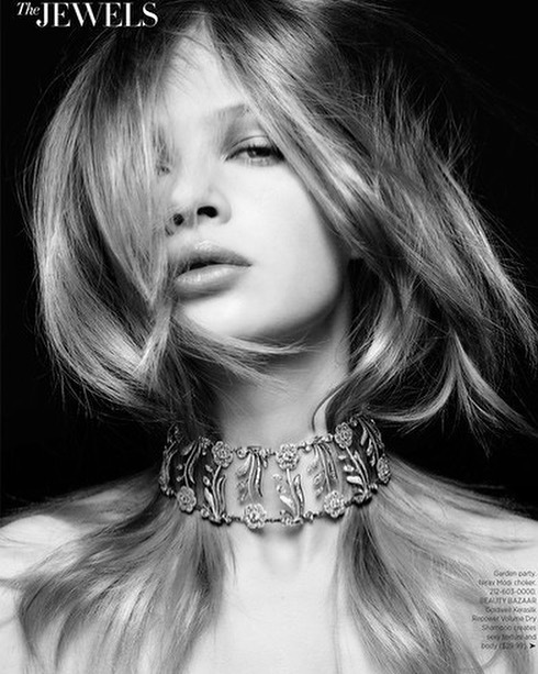 Monochrome portrait of a young woman with light hair wearing a floral choker. Fashion shot with shallow depth of field and elegant jewelry.