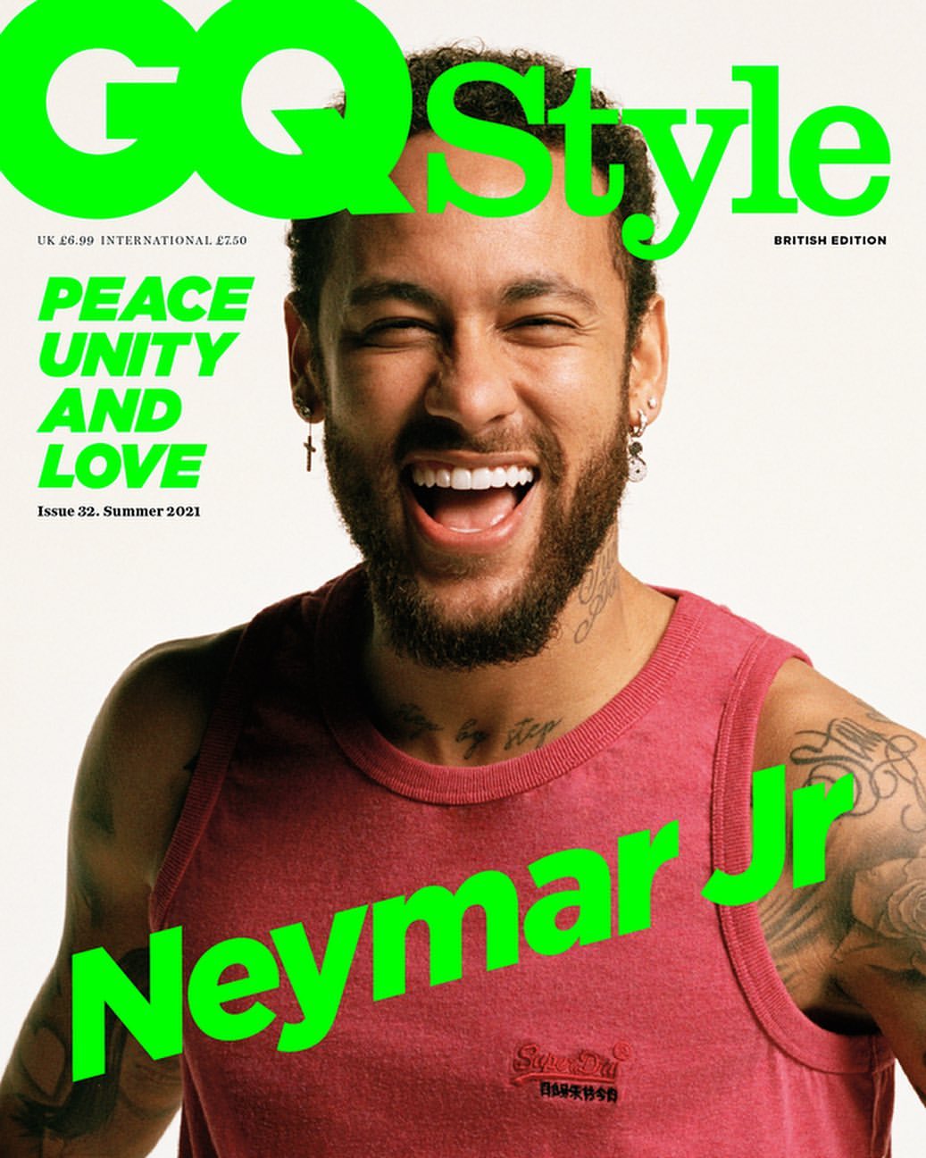 Magazine cover featuring a smiling man with a beard wearing a red tank top against a white background with overlaid green text.