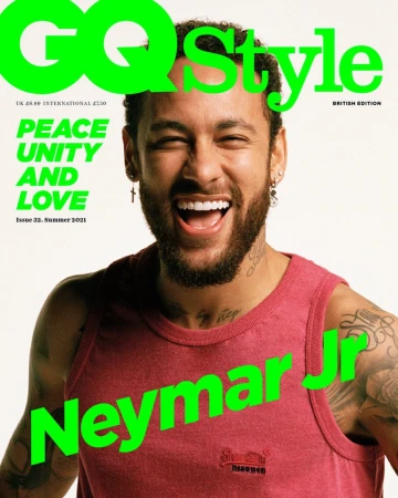 Magazine cover featuring a smiling man with a beard wearing a red tank top against a white background with overlaid green text.