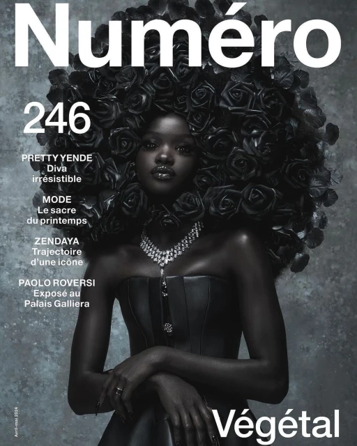 Magazine cover featuring a black model adorned with black roses, wearing a black strapless dress and a diamond necklace against a grey background.