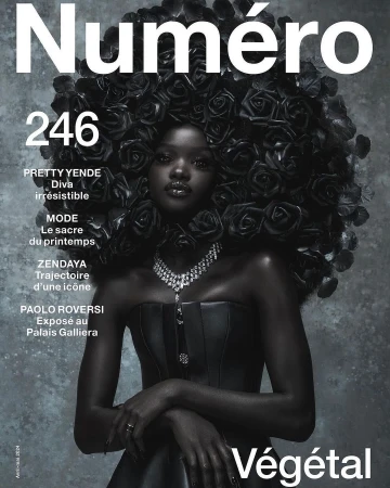 Magazine cover featuring a black model adorned with black roses, wearing a black strapless dress and a diamond necklace against a grey background.