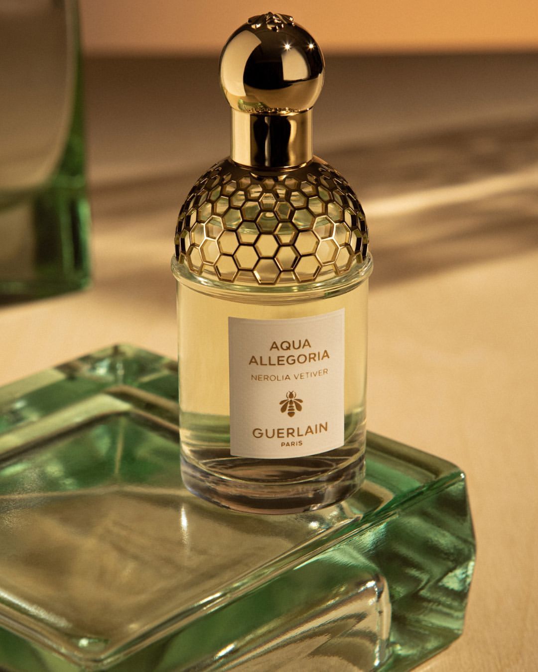 Guerlain Aqua Allegoria Nerolia Vetiver perfume bottle with golden cap and green glass base, showcased in a close-up studio shot.