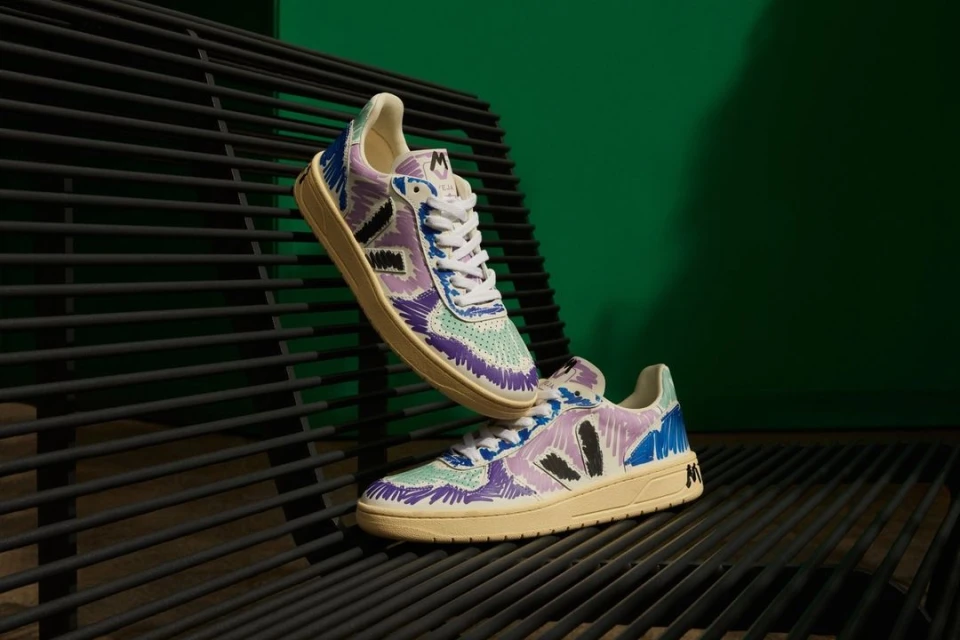 Artistic sneaker display: two colorful sneakers on a black metal grate against a vivid green backdrop, showcasing modern footwear design.