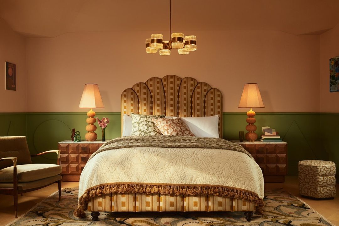 Interior bedroom view featuring a patterned scalloped headboard bed, two bedside lamps, and green and peach walls photographed by Kensington Leverne.