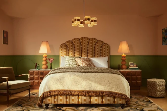 Interior bedroom view featuring a patterned scalloped headboard bed, two bedside lamps, and green and peach walls photographed by Kensington Leverne.