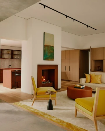 Stylish living room interior with yellow chairs, a brown fireplace, and contemporary art, creating a warm and inviting atmosphere.