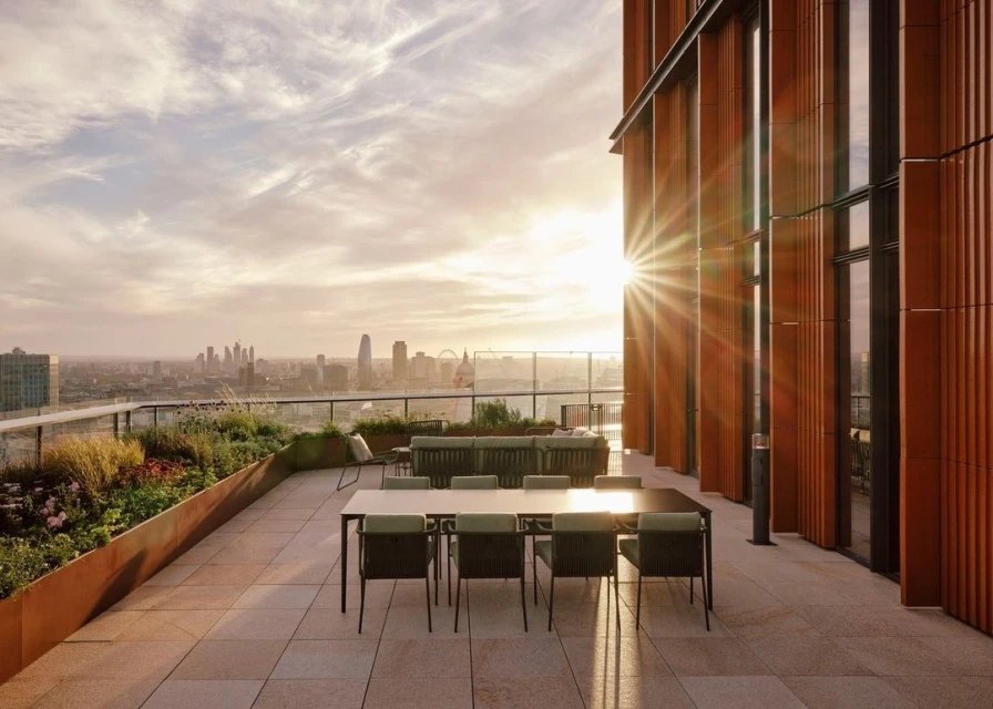 Rooftop terrace with dining table and city skyline in the background, illuminated by a golden sunset, creating a peaceful outdoor space.