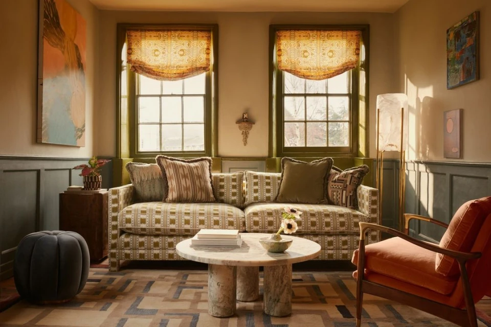 Cozy living room interior featuring a patterned sofa, round marble coffee table, and stylish decor, enhanced by warm, natural light.