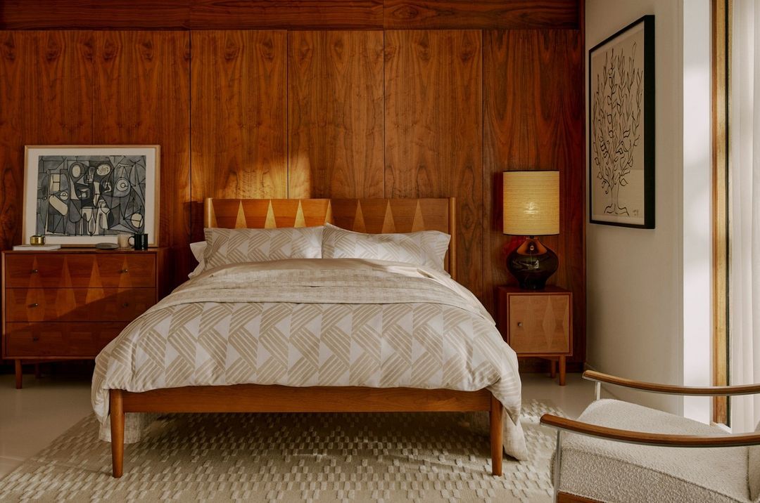 Mid-century modern bedroom featuring a wooden bed with patterned bedding, wood paneling, and stylish decor create a warm and inviting space.