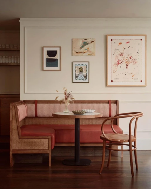 Interior view of a cafe booth with a marble-topped table, wooden chair, and artwork on the wall, creating a cozy dining ambiance.