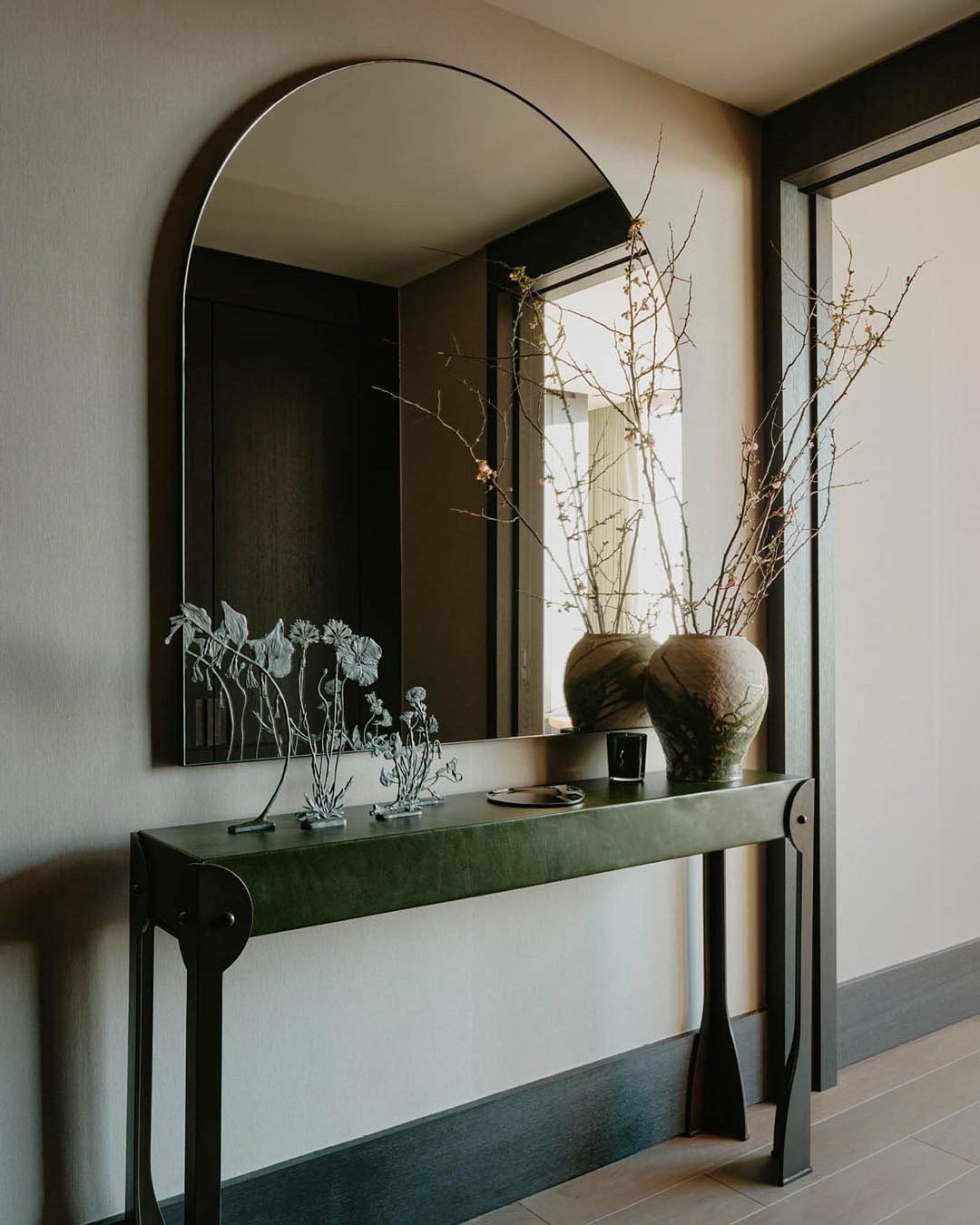 Interior design featuring a modern console table with decorative objects and a mirror, creating a stylish and inviting entryway.
