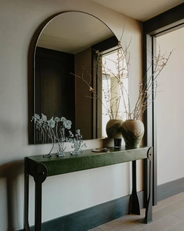 Interior design featuring a modern console table with decorative objects and a mirror, creating a stylish and inviting entryway.