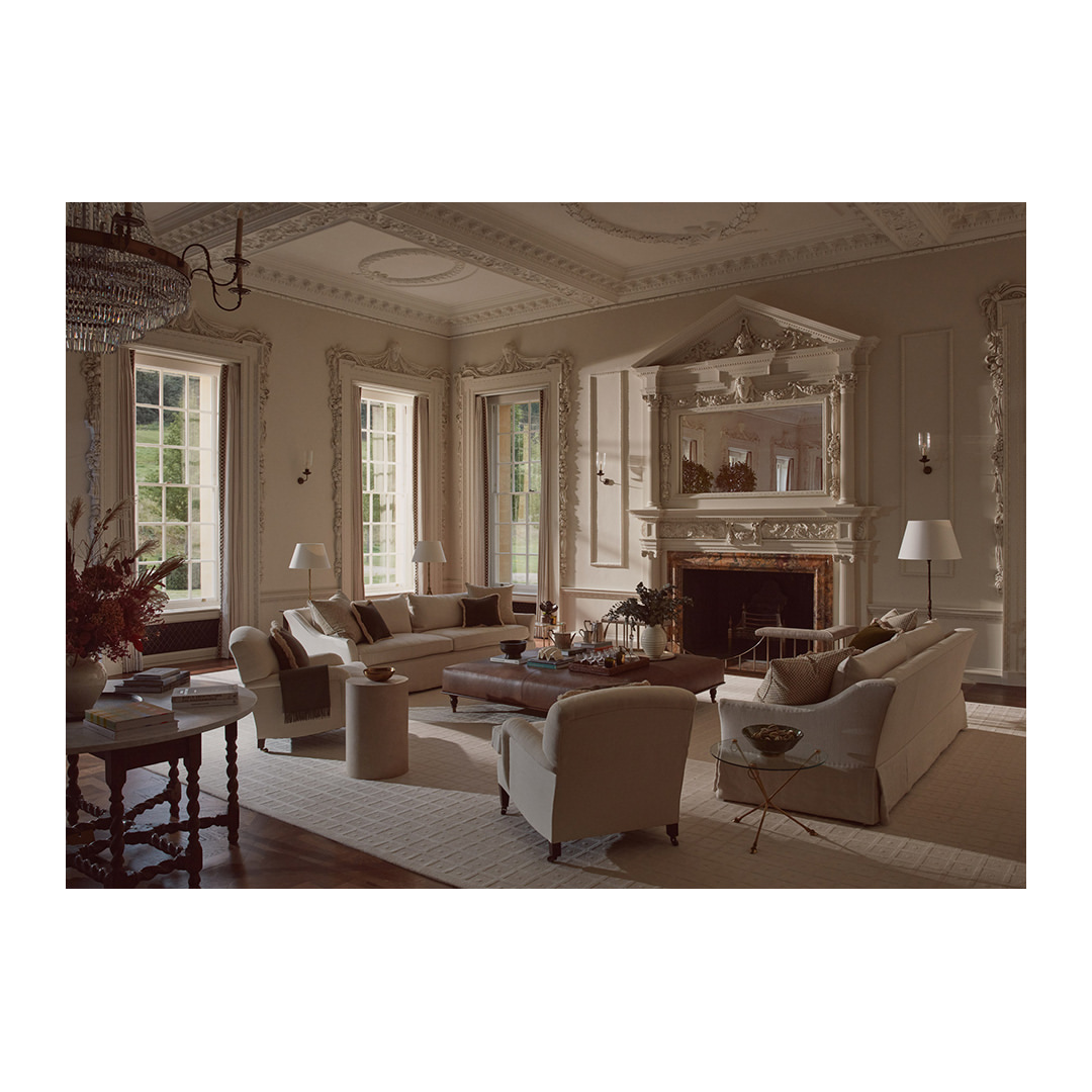 Elegant interior with cream-colored sofas, fireplace, and bright windows, showcasing a luxurious and well-lit living space.