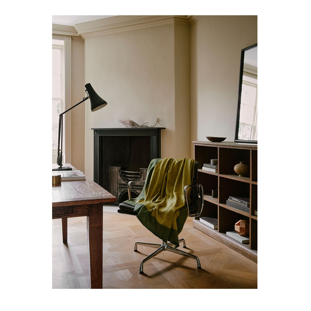 Interior design featuring a desk, chair with green throw blanket, a bookshelf, a fireplace, and hardwood floors.
