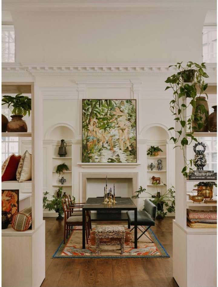 Elegant dining room features a dark wood table, upholstered chairs, an animal print stool, and a framed painting above a white fireplace.