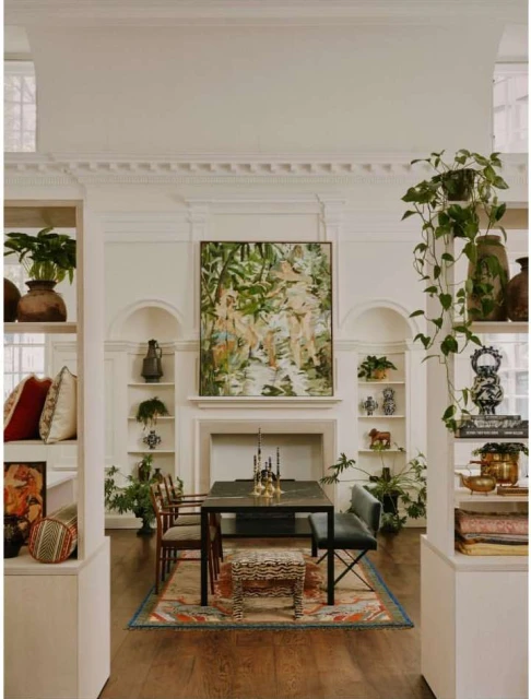 Elegant dining room features a dark wood table, upholstered chairs, an animal print stool, and a framed painting above a white fireplace.