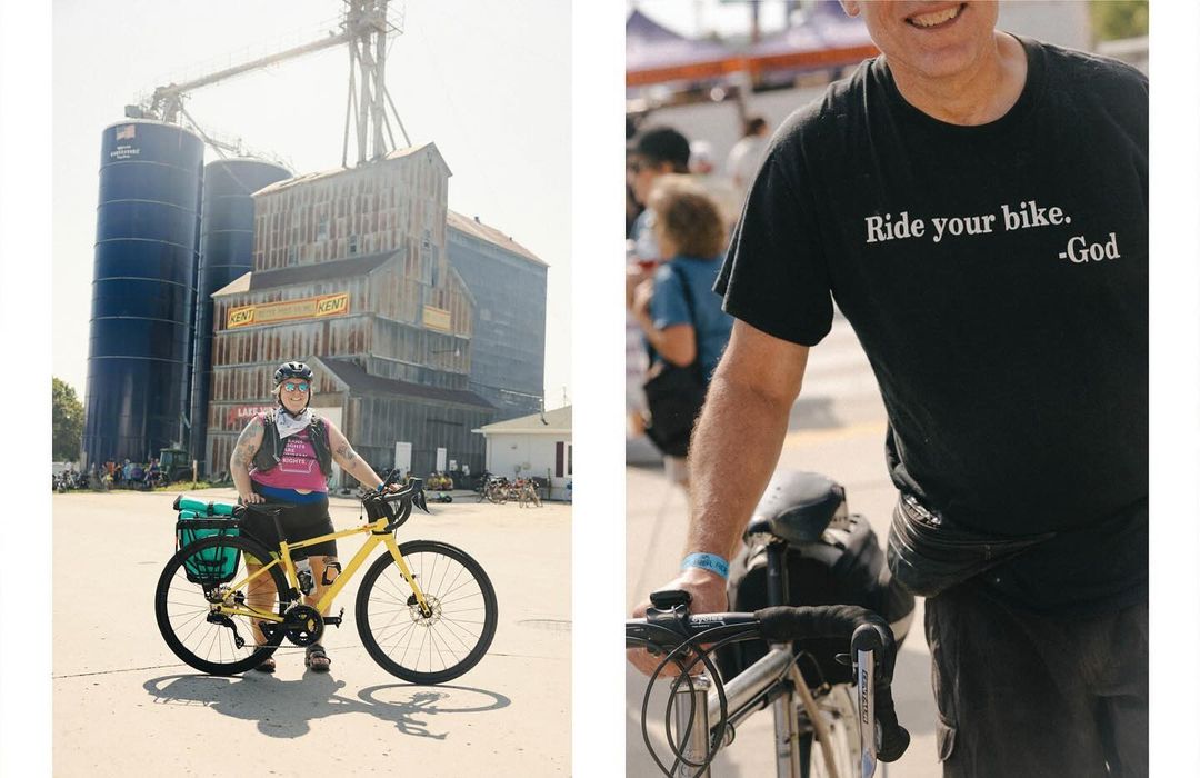 A woman stands with her touring bicycle in front of an old grain elevator. A man's torso is visible with a slogan t-shirt.