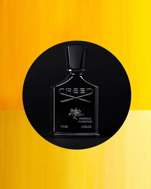 Elegant black Creed Absolu Aventus perfume bottle stands out against a vibrant yellow backdrop and a sleek black circular foreground.