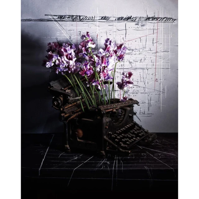 Antique typewriter adorned with vibrant purple flowers against a textured backdrop, creating a captivating contrast of old and new.