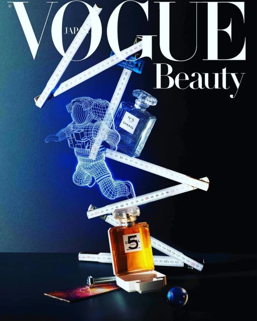 Vogue Japan cover featuring an astronaut figure, perfume bottles, and a measuring tape, creatively arranged on a dark surface.