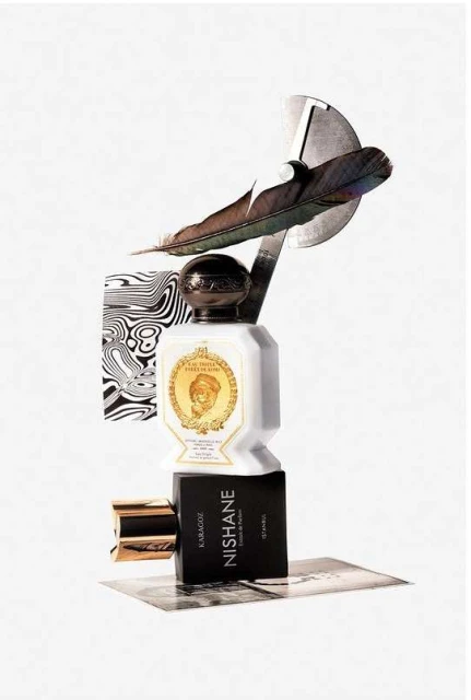 Elegant still life composition with a perfume bottle, feather, and geometric shapes against a clean white backdrop.