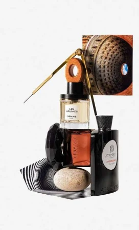Still life photo of stacked perfume bottles with compass and architectural element against a white backdrop. Luxury fragrance concept.