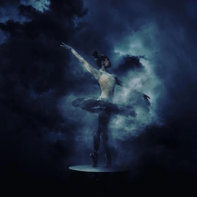 Ballerina strikes a pose in the ethereal blue studio, her tutu suspended in a swirling cloud of powder against a dark backdrop.