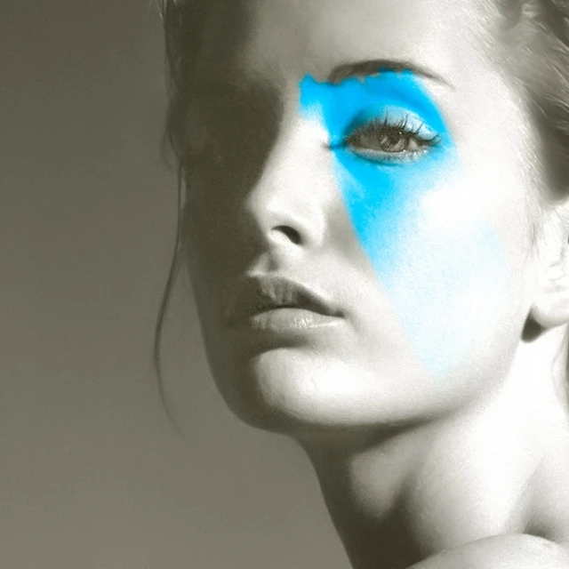 Monochromatic portrait of a fair-skinned woman with bright blue makeup around her eye, creating a striking, artistic beauty image.