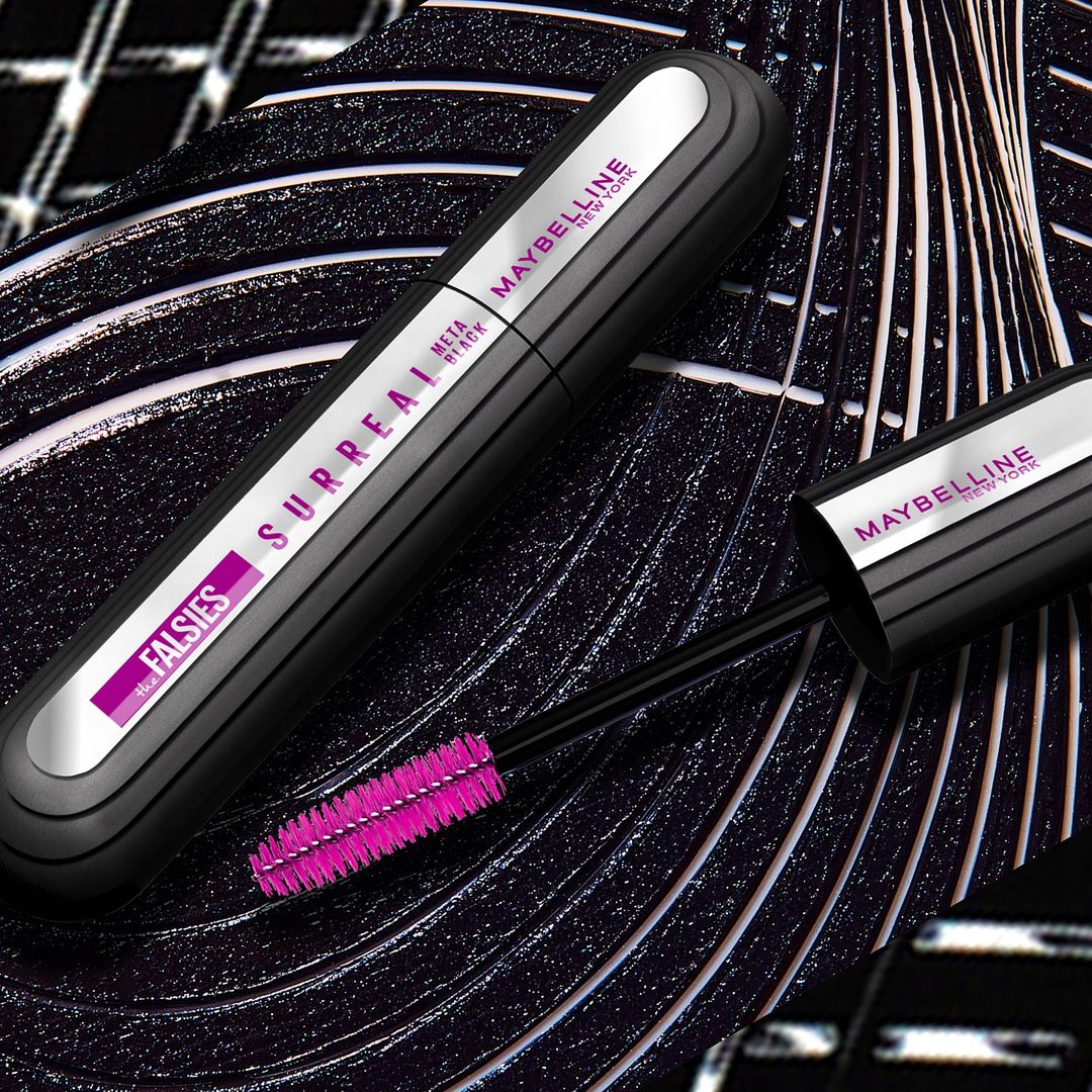 Close-up of Maybelline mascara tube and wand with purple brush, set against a patterned black and white background, product shot.