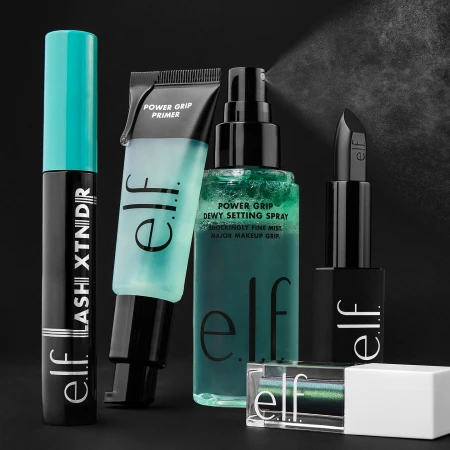E.l.f. Cosmetics product lineup: mascara, primer, setting spray, lipstick, and eyeshadow on a dark background with a subtle mist effect.