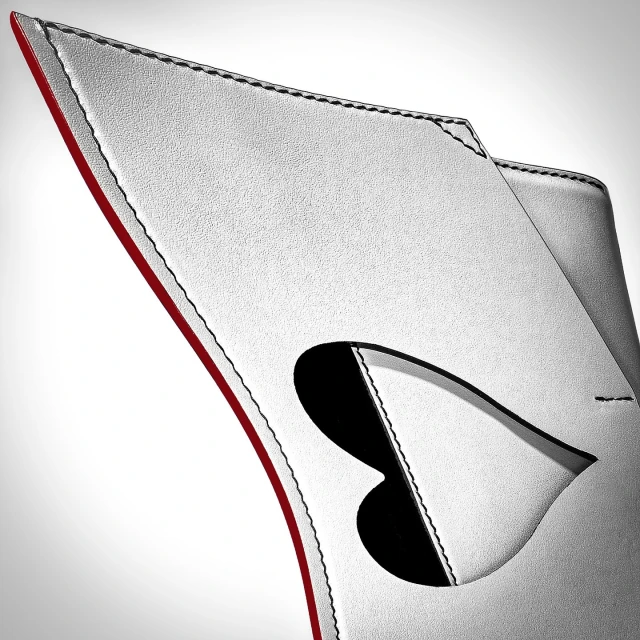 Close-up of a white leather product with a red edge, black stitching, and a heart-shaped cut-out, showcasing the product's texture and design.