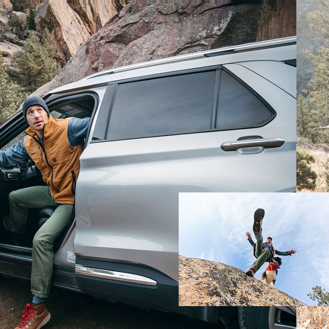 Man wearing a beanie, vest, and jeans steps out of a silver SUV in a mountain setting with rock formations and green trees in the background.