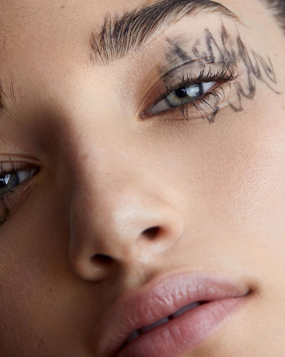 Close-up portrait of a woman with striking eye makeup, showcasing artistic beauty and bold cosmetic design in a studio setting.