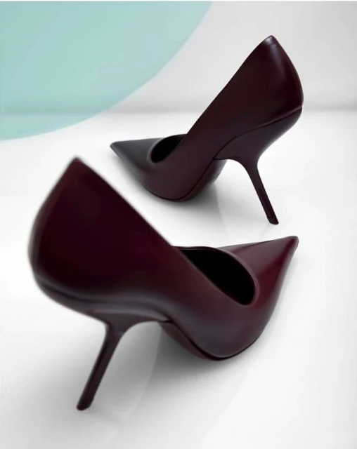 Studio shot of a pair of maroon leather stiletto heels with pointed toes on a gradient background. Fashion, style, footwear.