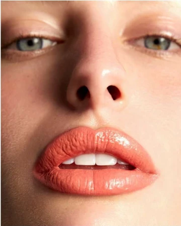 Close-up portrait focusing on glossy coral lipstick and blue eyes of a woman by photographer Kimber Capriotti.
