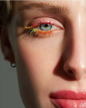 Close-up beauty portrait by Kimber Capriotti focusing on an eye with rainbow gradient eyelashes and pink lips.