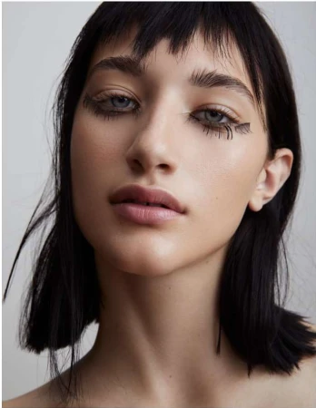 Close up portrait of a young woman with dark hair, blunt bangs, and artistic eye makeup by photographer Kimber Capriotti