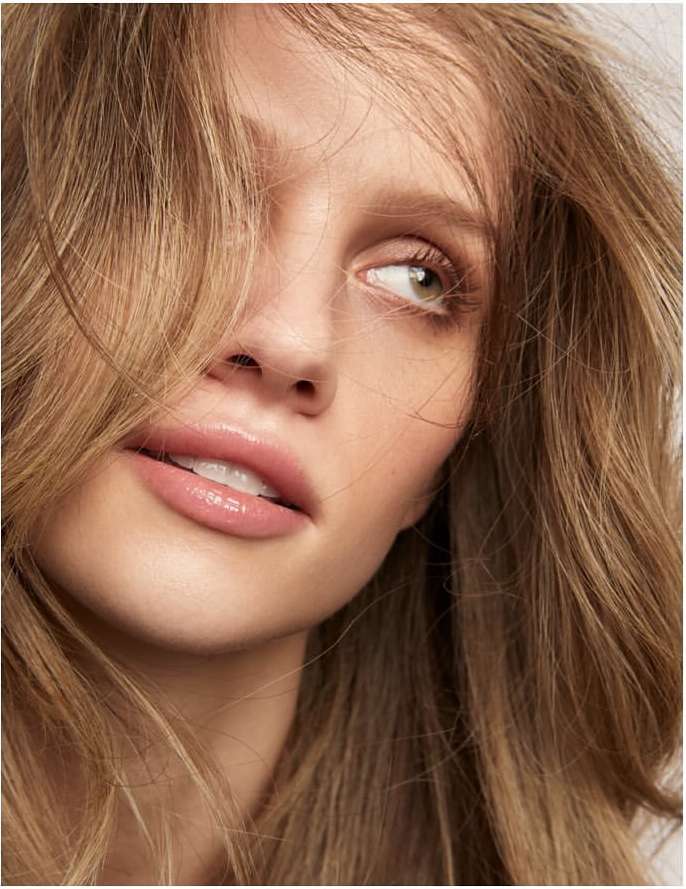 Close-up beauty portrait of a woman with long blonde hair framing her face and glossy lips, captured by Kimber Capriotti.