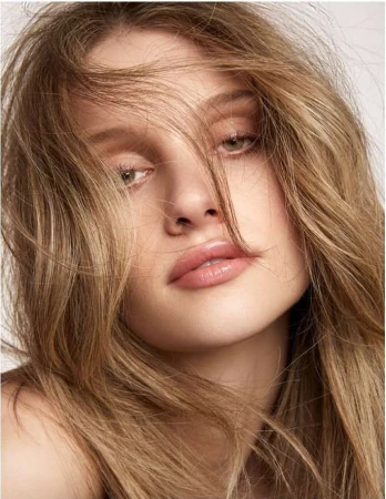 Close-up beauty portrait of a woman with tousled blonde hair across her face, captured by photographer Kimber Capriotti.