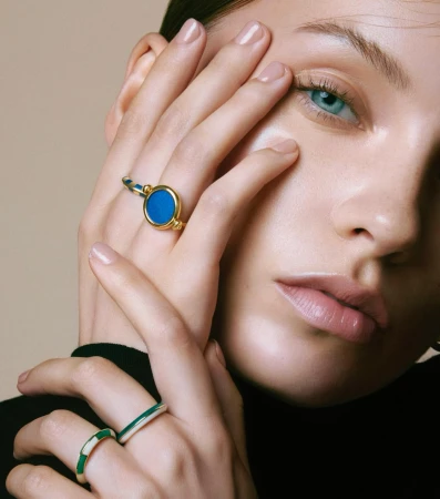 Close-up portrait of a woman wearing gold rings with blue and green enamel inlay, photographed by Kinya.
