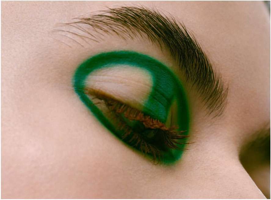 Close-up portrait of a closed eye featuring vibrant green graphic eyeliner and mascara on eyelashes by Kinya