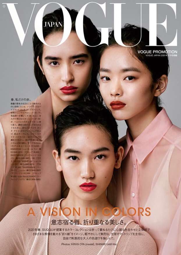 Vogue Japan cover features three young Asian women with bold red lipstick and sheer tops against a light gray backdrop in soft lighting.