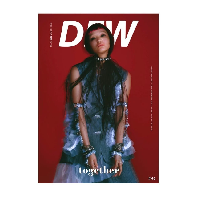 Magazine cover with a portrait of a woman with dark hair and dark eyes, wearing a textured sleeveless top against a red background.