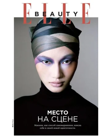 Elle Beauty magazine cover featuring a woman with creative makeup and a head wrap, set against a grey backdrop with bold typography.