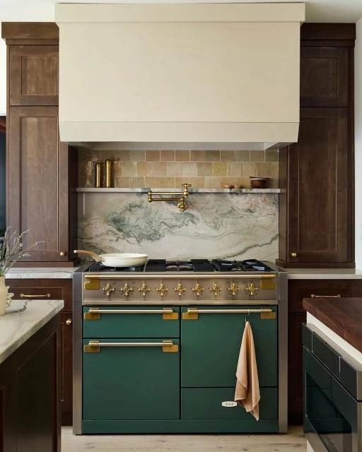 A modern kitchen features a green range cooker, set against a backsplash of marble and tan tile, complemented by dark wood cabinetry.