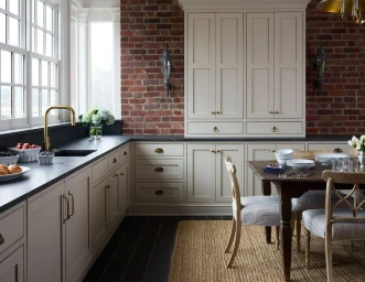 Modern kitchen with cream cabinetry, exposed red brick wall, dark countertops, and a wooden dining table by Kip Dawkins