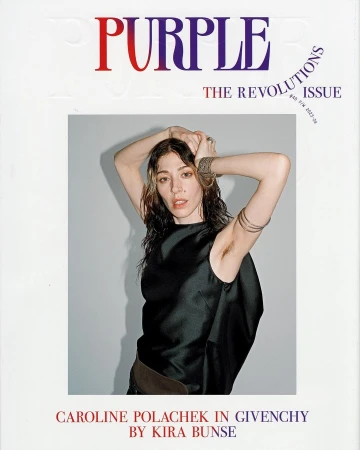 Caroline Polachek wearing a black sleeveless top with arms raised, photographed by Kira Bunse against a plain grey backdrop.